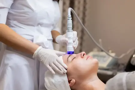 Clienta in timpul unei proceduri faciale cu aplicator cosmetic